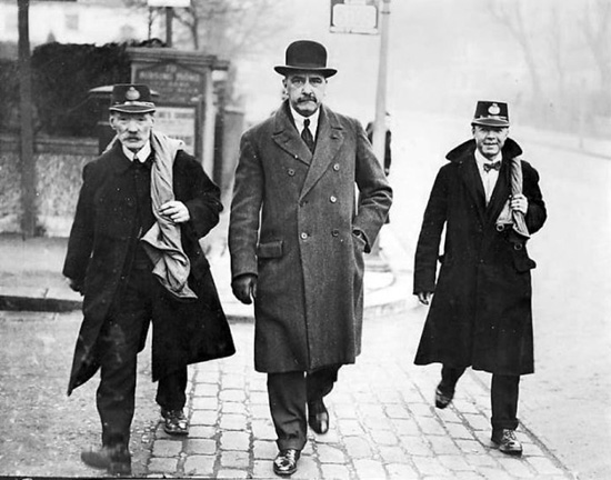 Reginald Bray escorted by two postmen while being 'transported' as a human letter.